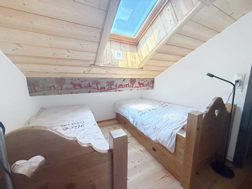 Chambre douillette sous les combles avec deux lits en bois, puits de lumière et poutres apparentes aux Tanières de Montgenèvre