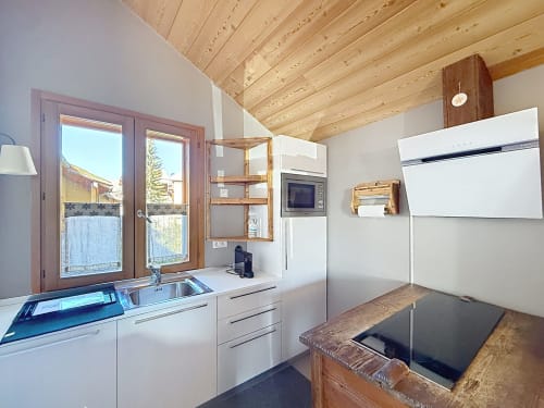 Cuisine moderne du duplex Le Flocon du Clocher aux Tanières de Montgenèvre avec appareils blancs et poutres en bois