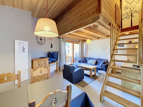 Séjour duplex du Flocon du Clocher avec canapé bleu, escalier en bois et vue sur la montagne à Montgenèvre