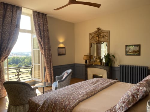 Chambre élégante au Château de Vaux Morvan avec lit, cheminée, miroir orné et balcon donnant sur la campagne d'Étang