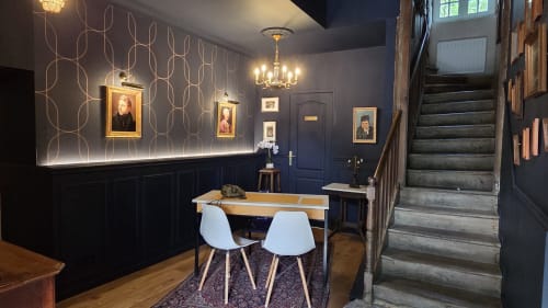 Élégant vestibule du Manoir de la Bégaudière avec murs bleus, galerie de portraits, lustre et salle à manger contemporaine