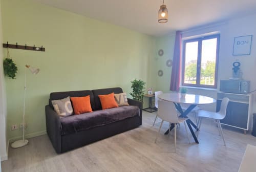 Appartement T2 moderne à la Résidence Kelys Boulogne-sur-Mer : canapé noir, table à manger, bureau, murs vert pâle, vue sur la ville