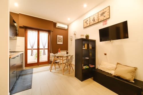 Loft St Peter 83 a Roma: monolocale moderno con cucina, zona pranzo, scaffalature nere, divano, TV a parete e ambiente caldo