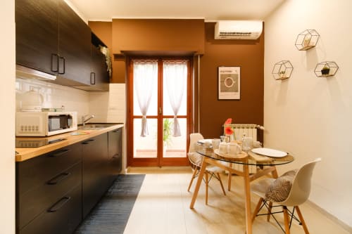 Cucina e zona pranzo moderne nell'appartamento St Peter 83 Loft a Roma, con mobili neri, dettagli in legno e tavolo rotondo
