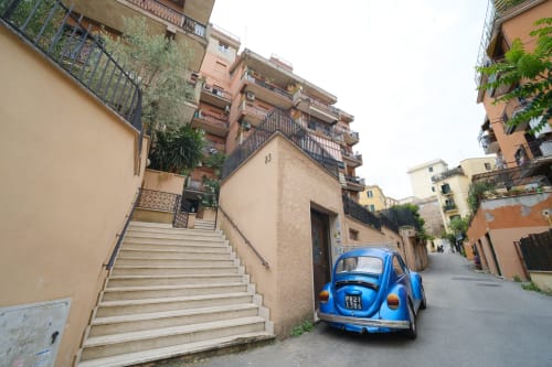 Vintage Beetle blu parcheggiata su affascinante strada romana tra edifici in terracotta e scalinata in pietra