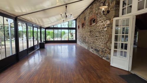 Véranda ensoleillée aux parquets bois et murs en pierre du Manoir de la Bégaudière, Mont-Dol