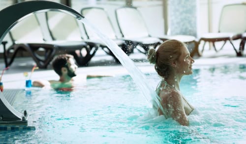 Enfant profitant de la piscine intérieure de l'hôtel spa Eucalyptus à El Ghazouane avec toboggan aquatique et chaises longues