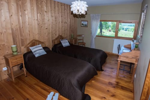 Chambre spacieuse de chalet montagnard avec deux lits, boiseries, et vue sur la vallée de Lans en Vercors