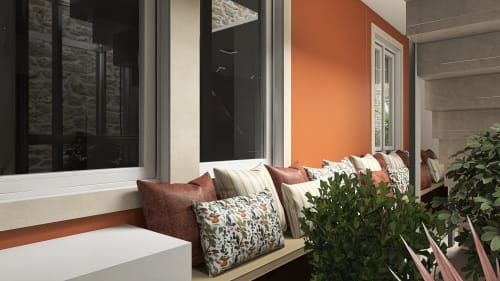 Cozy window seat at Feel Sintra B&B with orange accent wall, patterned pillows, and plants