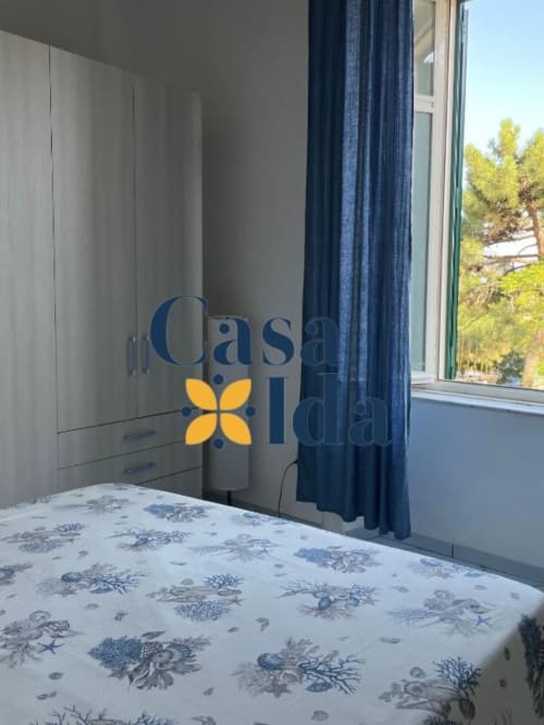 Camera luminosa a Casa Ida con biancheria a motivi, guardaroba moderno, tende blu navy e finestra con vista sul mare a Vietri, Italia