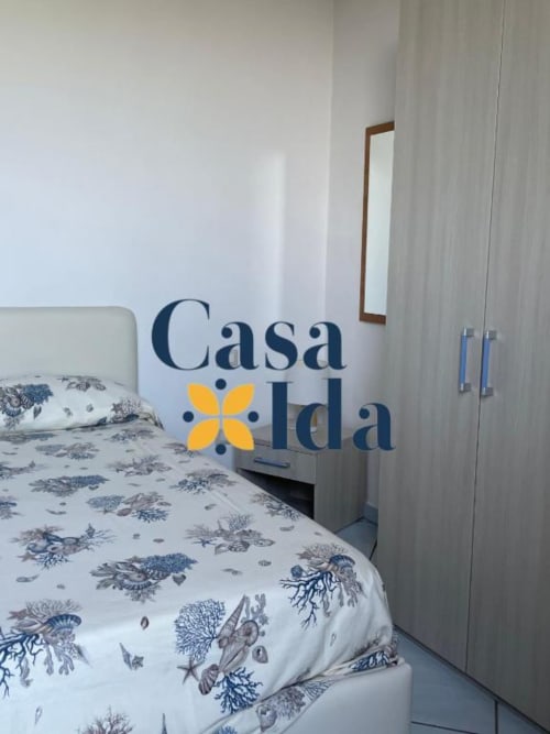 Camera da letto a Casa Ida a Vietri con biancheria floreale, guardaroba moderno e pareti bianche