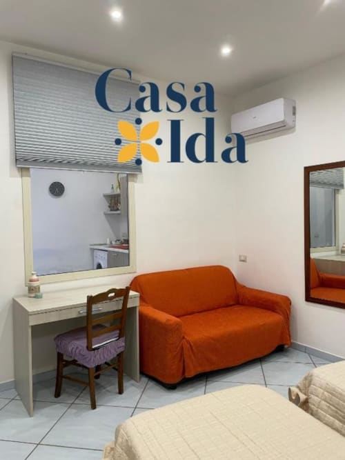 Soggiorno dell'appartamento Casa Ida a Vietri con divano arancione, scrivania e vista sul mare
