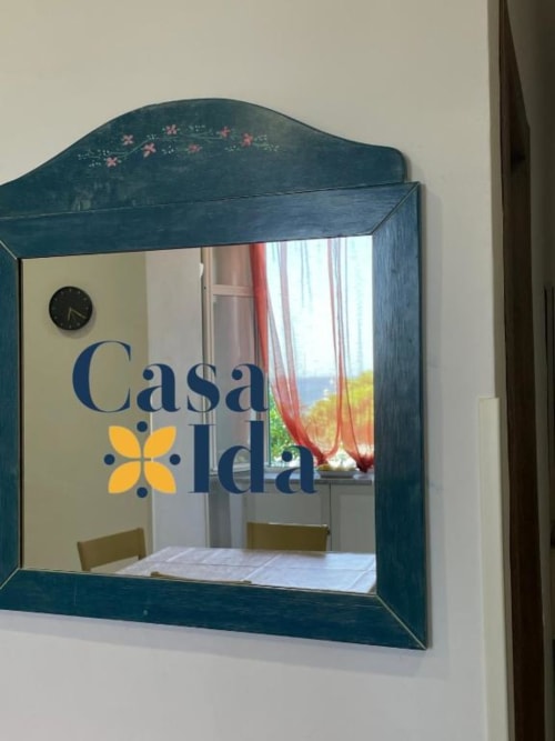 Specchio turchese con decorazioni riflette l'interno costiero di Casa Ida a Vietri, con vista mare e tende rosse