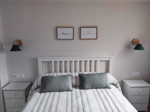Dormitorio moderno en Casa El Abuelo, apartamento rural en Bronchales, con cama de marco blanco, ropa de cama a rayas y arte decorativo en la pared