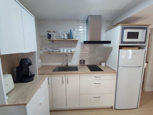 Cocina moderna en apartamento Casa El Abuelo, Bronchales, con muebles blancos, encimeras de madera, electrodomésticos y espacio abierto