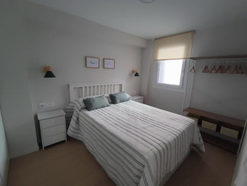 Dormitorio luminoso en Casa El Abuelo, Bronchales con ropa de cama a rayas, cabecero blanco, lámparas colgantes y luz natural