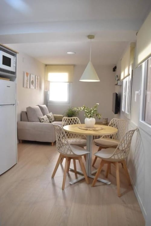 Cocina y comedor modernos con mesa redonda, sillas blancas, sofá e iluminación colgante en casa rural de Bronchales