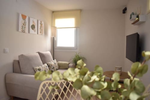 Luminoso salón moderno en apartamento Casa El Abuelo, Bronchales, con sofá gris, TV plana, plantas en maceta y