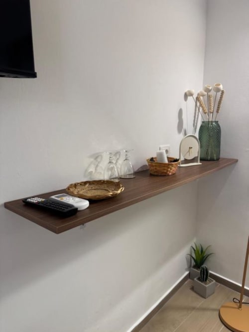 Mensola minimalista in legno nella camera Casa Ida con oggetti decorativi, piante e accessori su parete bianca