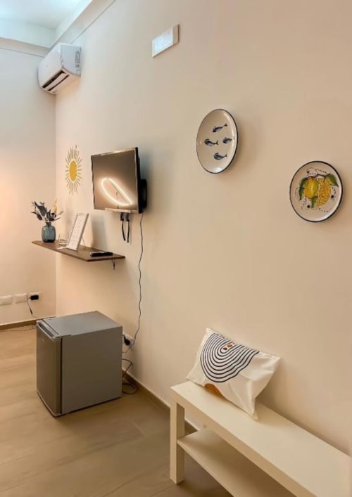 Camera Deluxe Casa Ida moderna a Vietri con TV a parete, piatti decorativi, arredi minimali e interni beige