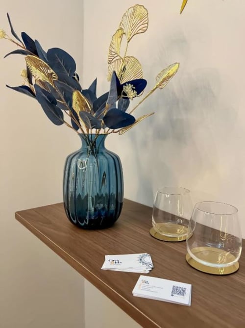 Elegante scrivania in legno a Casa Ida con vaso blu di fiori secchi, bicchieri e biglietti da visita a Vietri