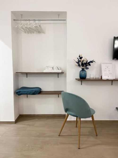 Moderna zona di lavoro nella spaziosa camera matrimoniale di Casa Ida con sedia turchese, scrivania in legno, scaffali a muro e arredi neutrali a Vietri
