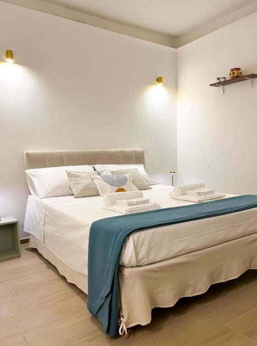 Camera moderna a Casa Ida B&B a Vietri con letto imbottito beige, plaid blu, biancheria bianca, illuminazione calda e piastrelle