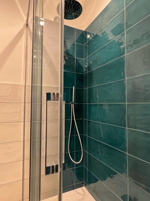 Moderno bagno con piastrelle verde e bianche, box doccia in vetro e soffione pioggia presso Casa Ida B&B a Vietri, Italia