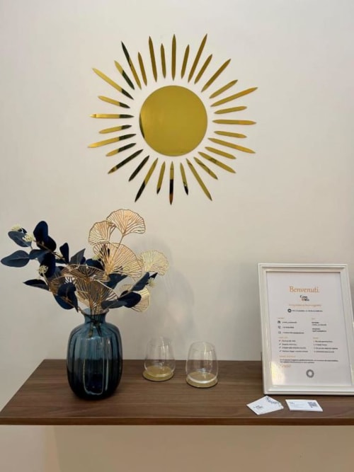 Elegante arredamento della scrivania a Casa Ida Vietri B&B con arte murale sole dorato, vaso blu con fiori secchi e cornice benvenuto