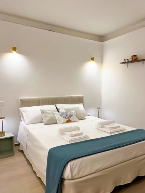 Camera moderna a Casa Ida a Vietri con letto matrimoniale, testata in crema, runner turchese, applique in ottone e biancheria bianca