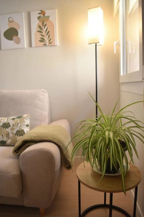 Acogedor rincón de la sala en apartamento Casa El Abuelo con sofá beige, planta en maceta, lámpara de pie y arte botánico en la pared