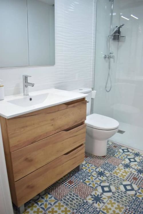 Baño moderno en Casa El Abuelo con mueble de madera, inodoro blanco, ducha con cristalería y azulejos decorativos