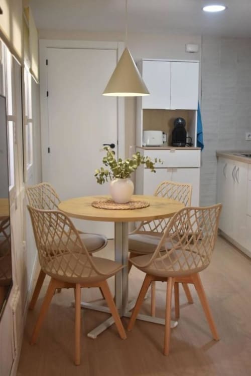 Comedor moderno con mesa redonda de madera, sillas tejidas y lámpara colgante en el apartamento Casa El Abuelo, Bronchales