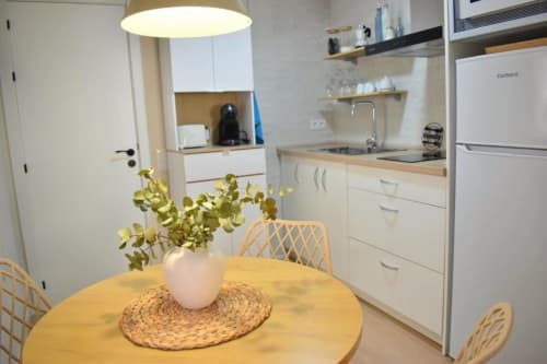 Moderna sala de cocina-comedor en el apartamento Casa El Abuelo, Bronchales, con mesa amarilla, muebles blancos y planta en maceta
