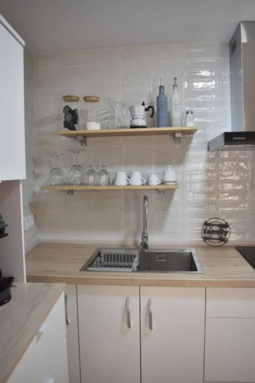 Cocina moderna con estantes de madera, muebles blancos y fregadero de acero inoxidable en el apartamento Casa El Abuelo, Bronchales