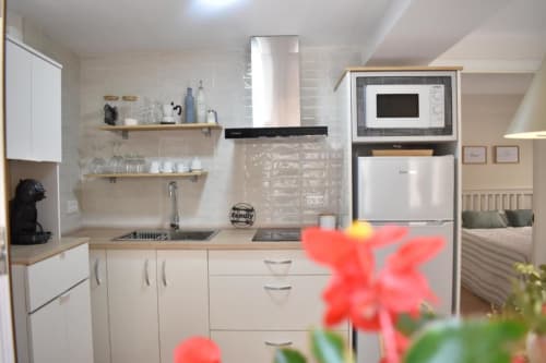 Cocina moderna en apartamento Casa El Abuelo, Bronchales con muebles blancos, encimera de madera, estufa, microondas y abierta