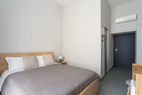 Modern bedroom at Darna Rooms Naples with wooden bed, air conditioning, grey flooring, dark door, and minimalist décor