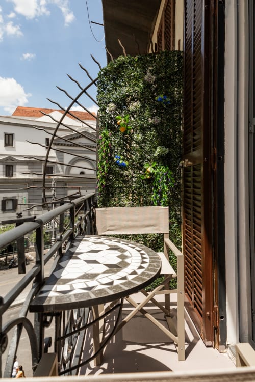 Balcony at Darna Rooms Naples with ivy-covered green wall, mosaic table, and city views
