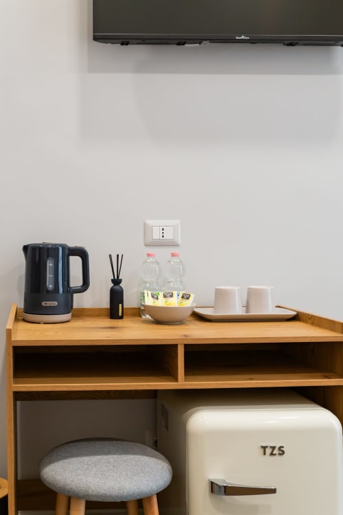Wooden desk with kettle, diffuser, water bottles, and amenities at Darna Rooms Naples BnB