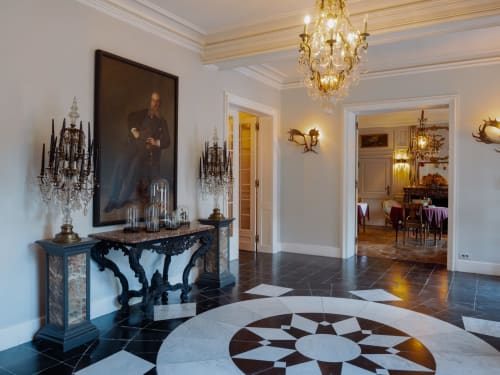 Elegant hallway at Castanea Business & Suites with marble floor pattern, ornate chandeliers, and classical portraits in