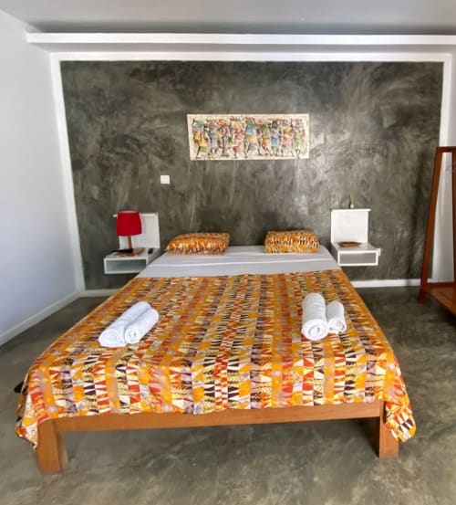 Cama com padrões coloridos no Hotel PZero em São Tomé, com toalhas enroladas, abajures e decoração artística na parede do quarto moderno