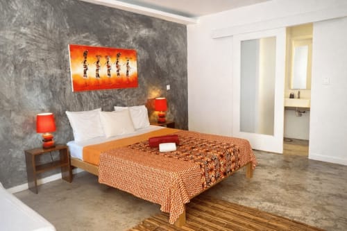 Quarto moderno do Hotel PZero em São Tomé com detalhes em laranja, parede texturizada cinza e cama com estrutura de madeira