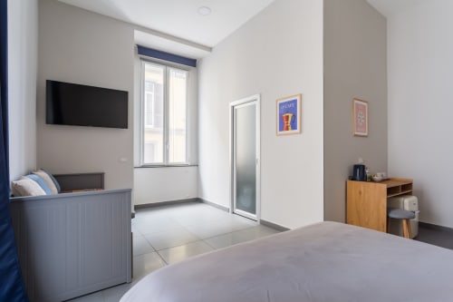 Darna Rooms Naples: Matrimoniale Deluxe bedroom with flat-screen TV, balcony access, wooden furniture, and modern amenities