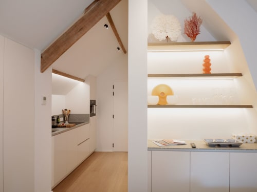 Modern kitchenette at Castanea Business & Suites with wooden beams, white cabinetry, and decorative shelving in Merelbeke,