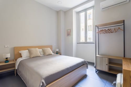 Moderna camera matrimoniale presso Darna Rooms Napoli con letto in legno, guardaroba, climatizzatore e luminosa luce naturale dalla finestra