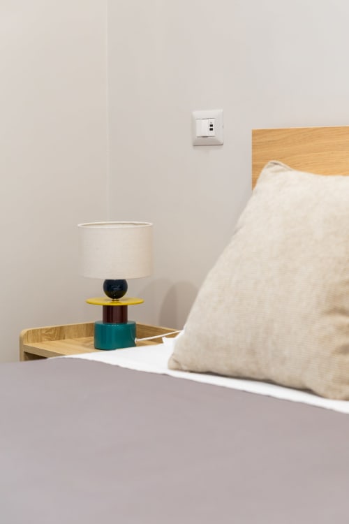 Bedroom nightstand at Darna Rooms Naples with modern lamp, wooden bed frame, and white linens