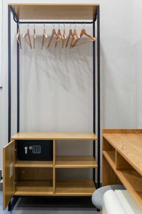 Modern clothing rack with wooden hangers in Darna Rooms Naples bedroom, featuring black frame and storage shelving below
