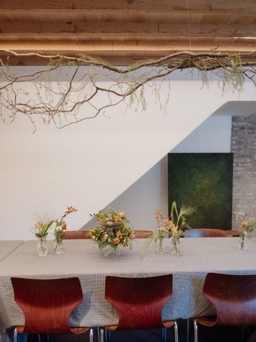 Modern dining space at Castanea Business & Suites with burgundy chairs, wooden branches, and floral arrangements