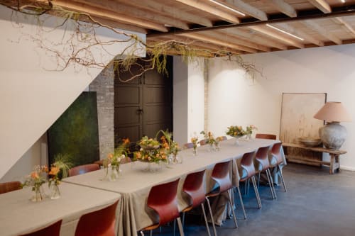 Elegant dining room at Castanea Business & Suites with long table, red chairs, hanging botanicals, and wooden beams.