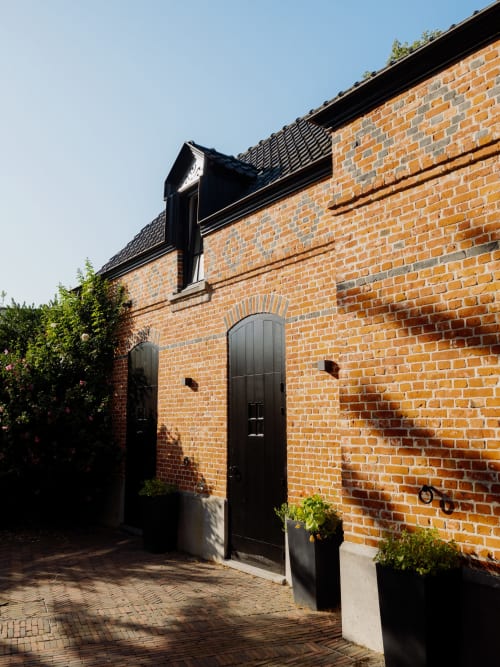 Red brick entrance of Castanea Business & Suites in Merelbeke-Melle with black doors and dormer window